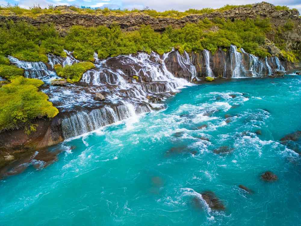 Hraunfossar waterfalls cascading into bright turquoise water in West Iceland.