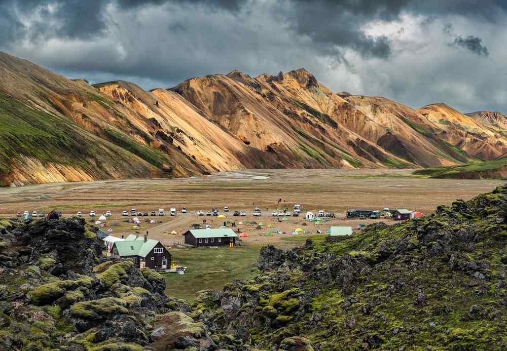 Landmannalaugar campsite surrounded by colorful mountains and dark lava fields.