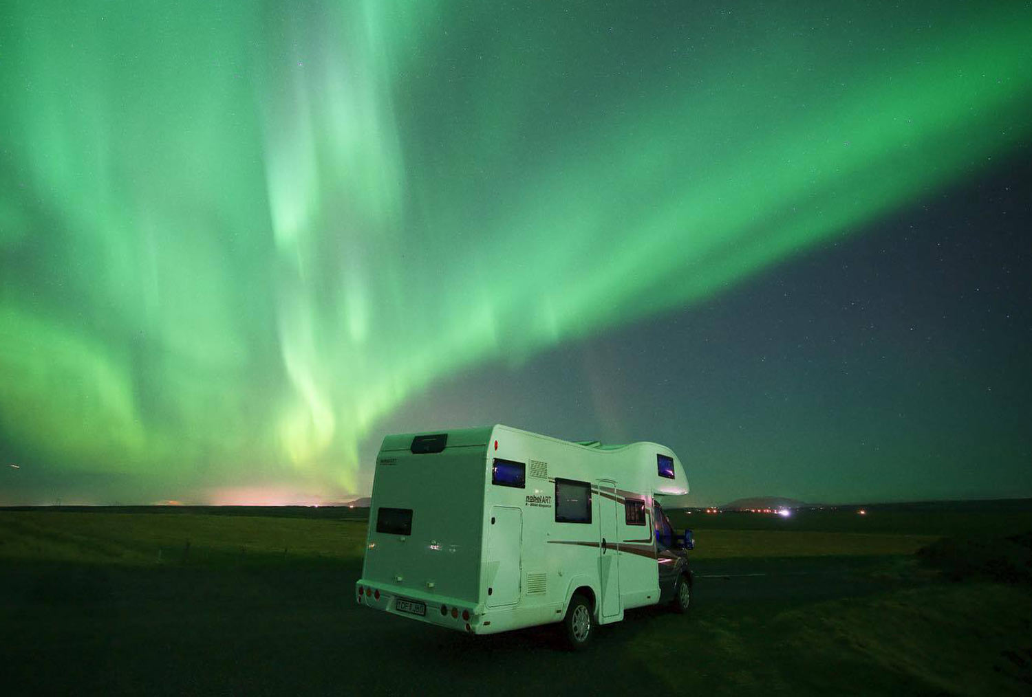 Large motorhome parked in Iceland with the Northern lights dancing in the sky