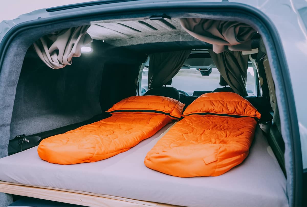 two bright orange sleeping bags inside of a compact camper in Iceland