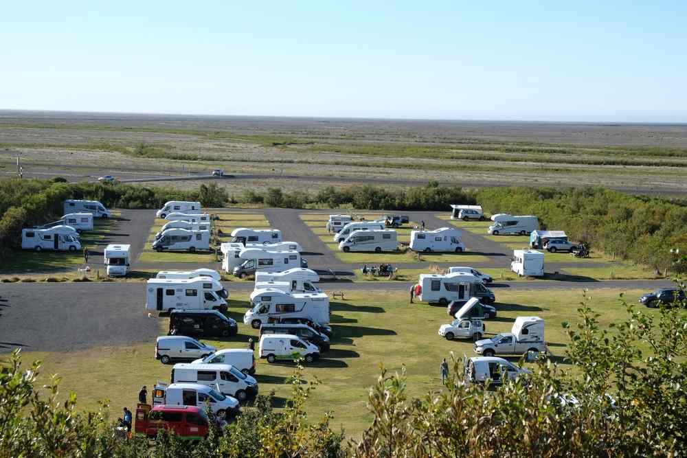 Campervans and motorhomes parked at an Icelandic campground surrounded by open landscapes.