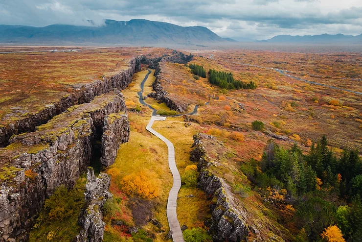 Overview of Iceland's Thingvellir National Park, with the yellowish and reddish vegetation typical of autumn and what appear to be storm clouds in the