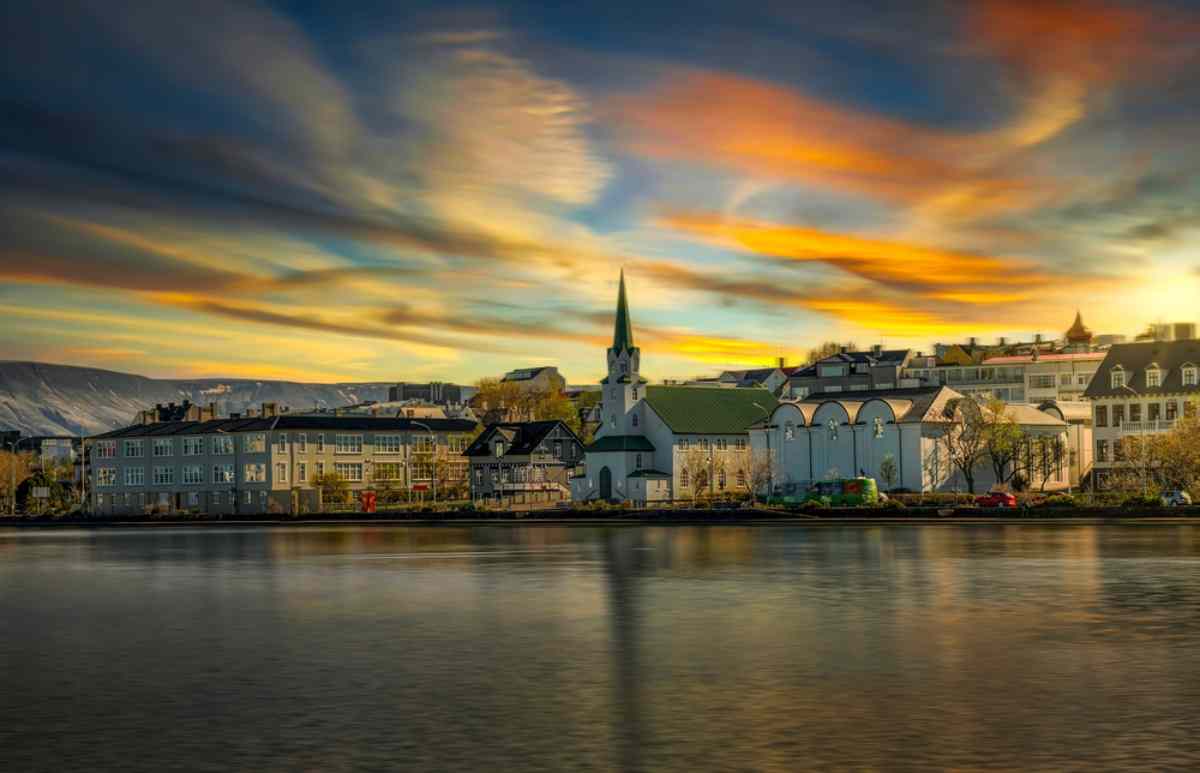 View of Reykjavik Bay during a cloudy day where you can see some of the towers of the city buildings and their reflection in the water.